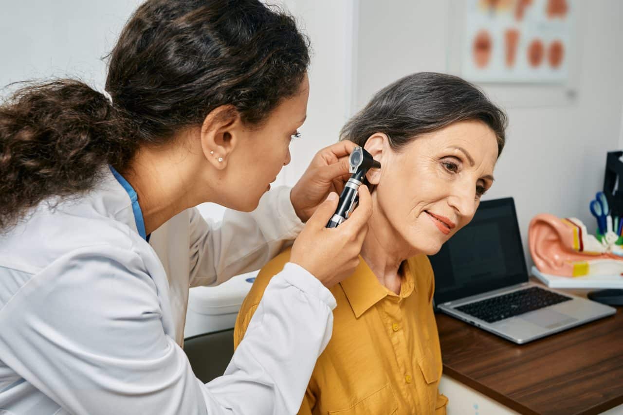 Senior woman receiving an ear exam from an audiologist.